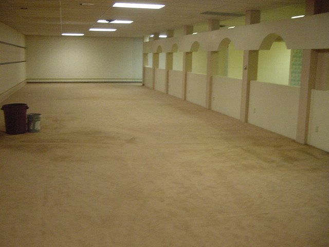 A large space with beige walls, floors and ceiling. Fluorescent panels provide muted lighting