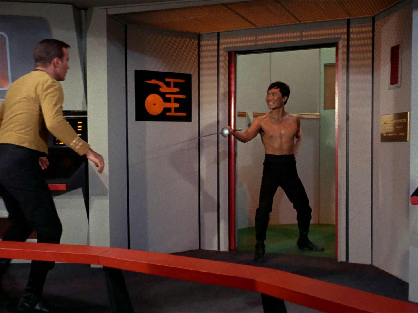 A shirless Sulu standing with a fencing sword in the doors of the Enterprise bridge turbolift