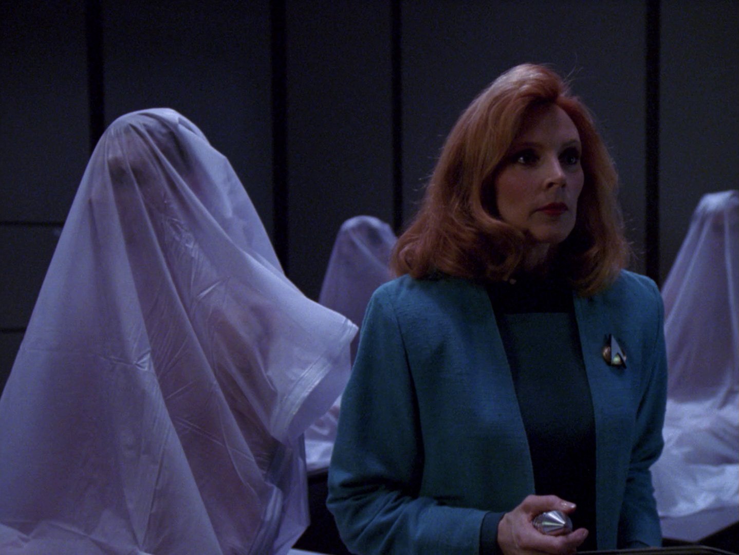 Doctor Beverly Crusher surrounded by shapes in a bodybags that are sitting up
